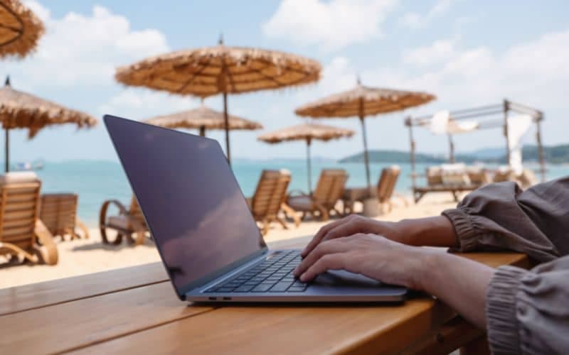 Person typing on laptop at a beach café in Marbella, Spain — digital nomad lifestyle and remote work destination 2025.